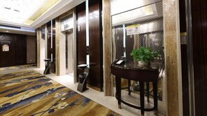 A hotel lobby with a patterned carpet, a reception desk, and a potted plant. - Huifeng Hotel (Shuyang)