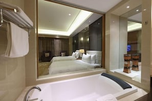 Habitación de hotel moderna con un espejo grande, una bañera y dos camas.