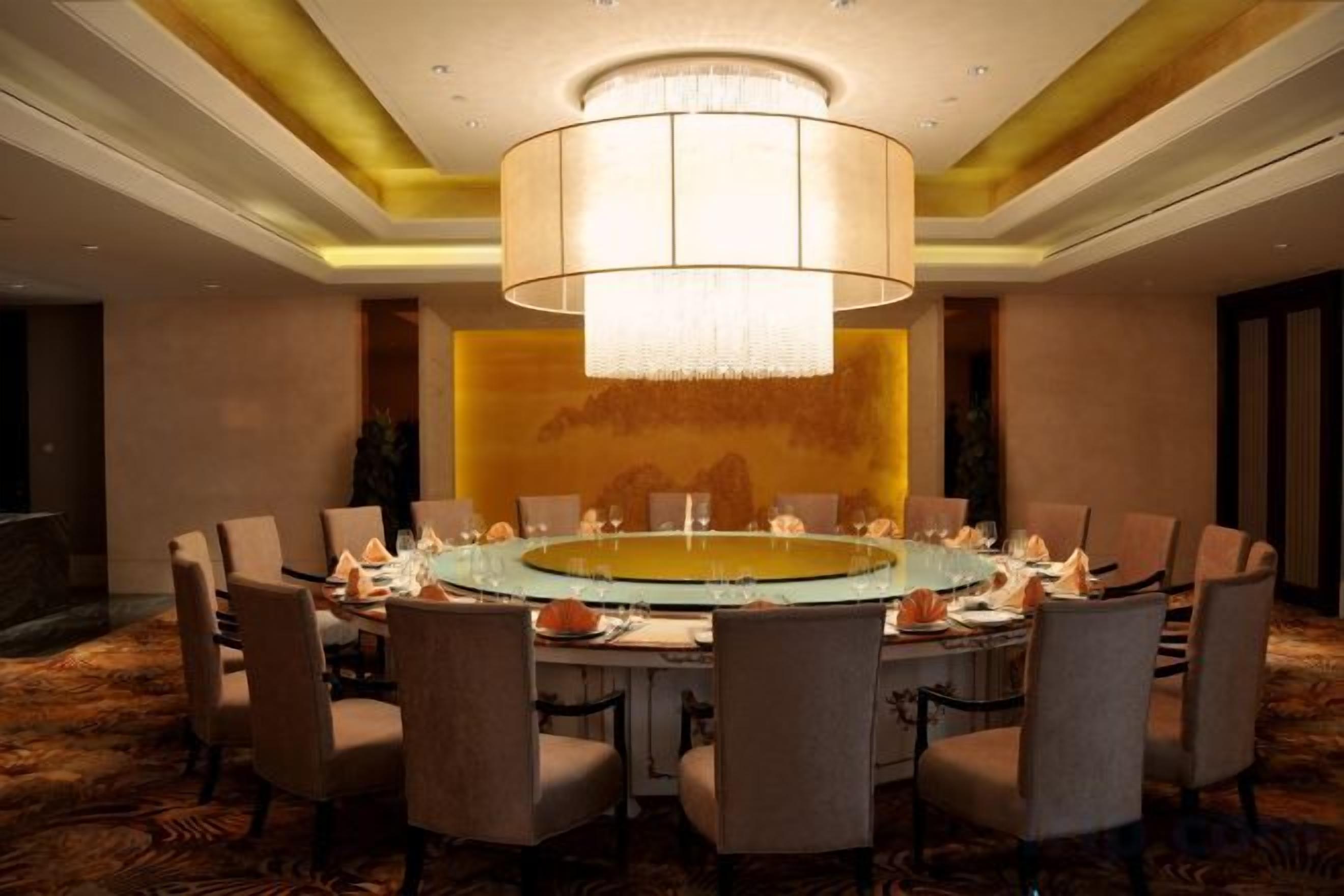 A conference room with a round table, chairs, and a chandelier.