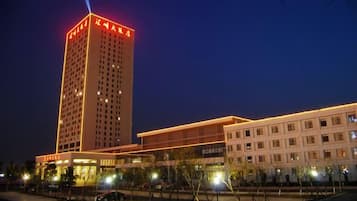 A multi-story hotel with a prominent tower, a covered walkway, and a parking area.