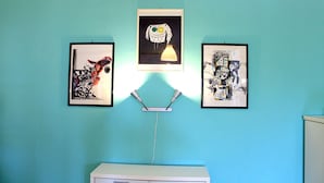 A wall with three framed artworks, a desk, and a lamp. - Cilento Loft (Ascea)