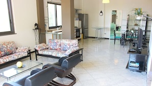 A spacious living area with a sofa set, a coffee table, and a television. - Cilento Loft (Ascea)