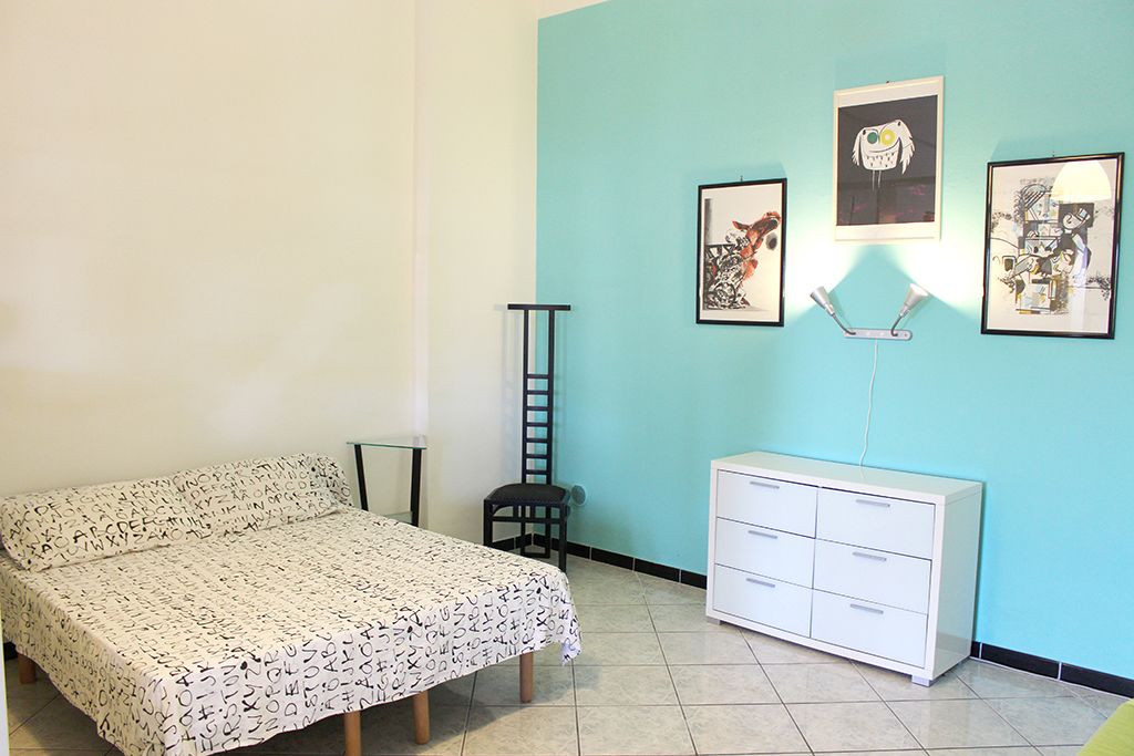 A bedroom with a bed, a white dresser, and three framed pictures on the wall.