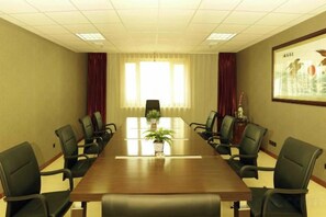 A conference room with a long table, chairs, a plant, and a framed picture on the wall. - Donglong Hotel (Harbin)