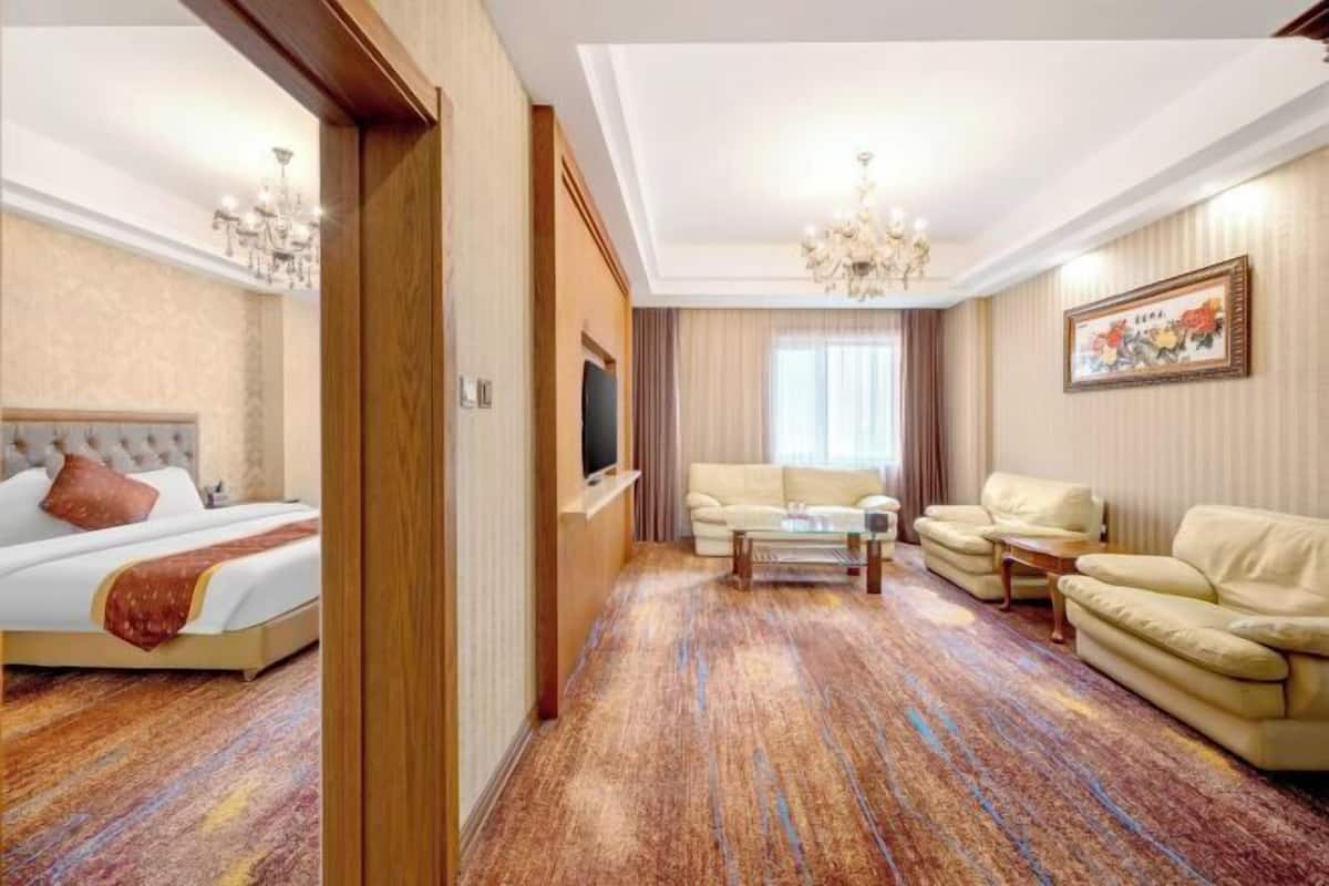 A hotel room with a bed, a sofa, a television, and a carpeted floor.