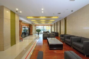 A hotel lobby with a reception desk, seating area, and a view of the outdoors. - Donglong Hotel (Harbin)