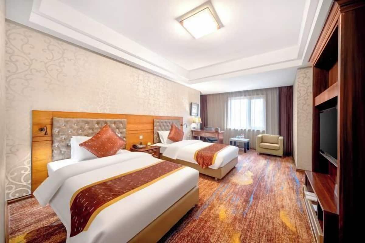 A hotel room with two beds, a TV, a desk, and a chair.