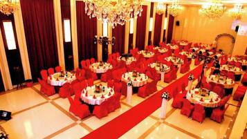 A banquet hall with round tables, red chairs, and a red carpet.
