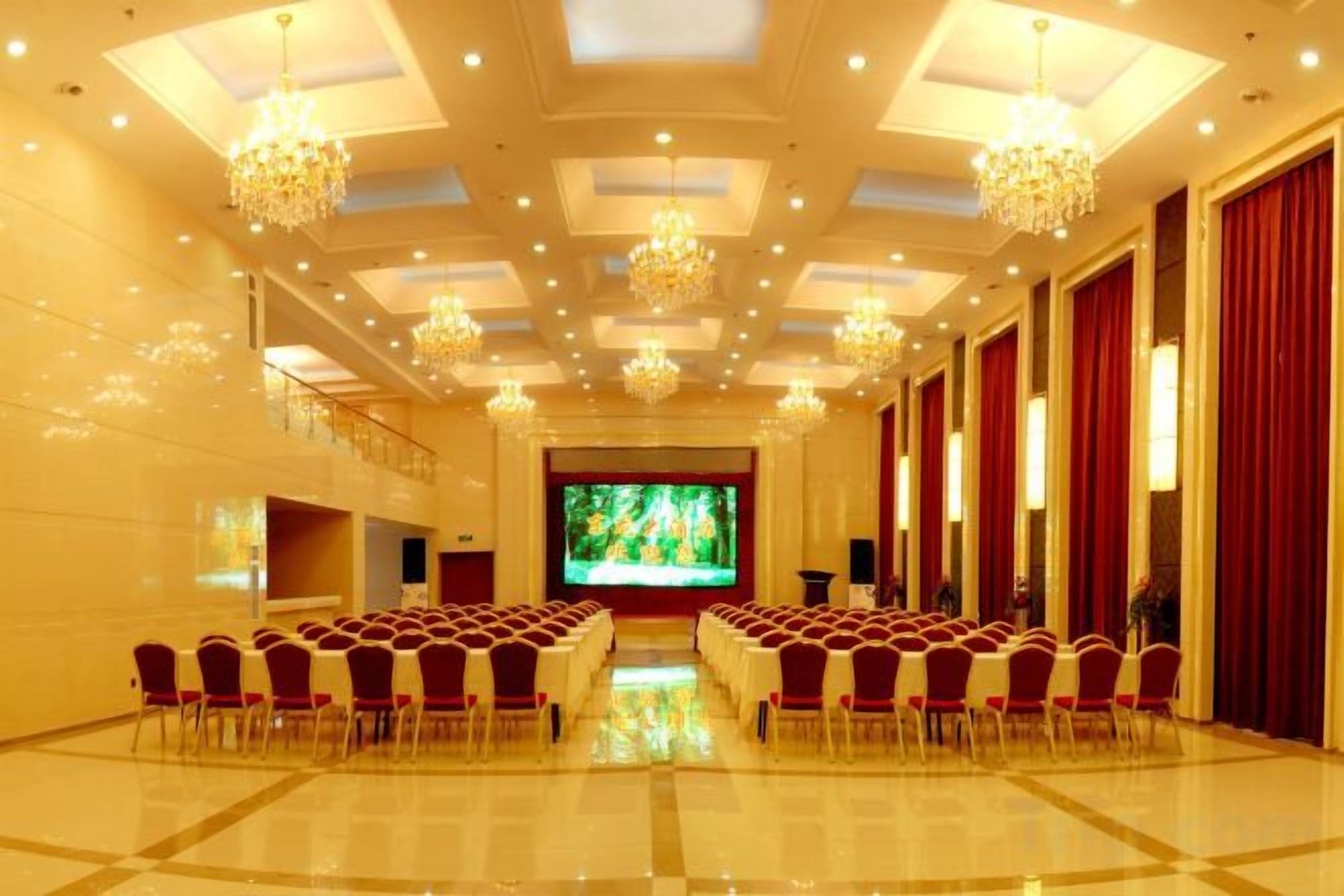 Un salón de conferencias con una larga mesa, sillas y una pantalla grande al frente.