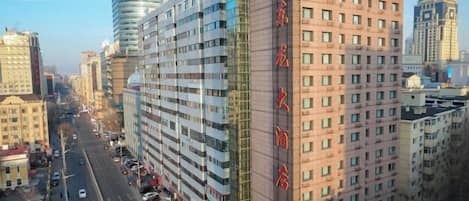 Un immeuble de grande hauteur, doté de nombreux étages, d’une entrée imposante et offrant une vue dégagée sur la rue.