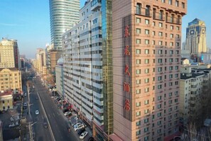 A high-rise building with multiple floors, a prominent entrance, and a clear view of the street below. - Donglong Hotel (Harbin)