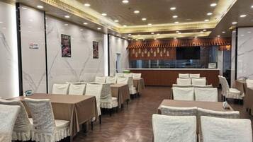 A restaurant with multiple tables and chairs, a counter, and a modern ceiling design.