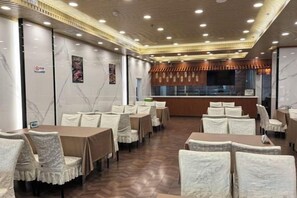 Un restaurante con varias mesas y sillas, una barra y un diseño de techo moderno.