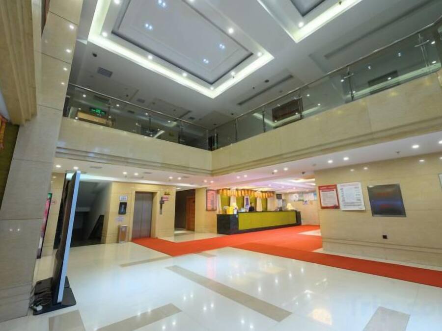 A multi-level hotel lobby with a glass railing, a reception desk, and a red carpet.