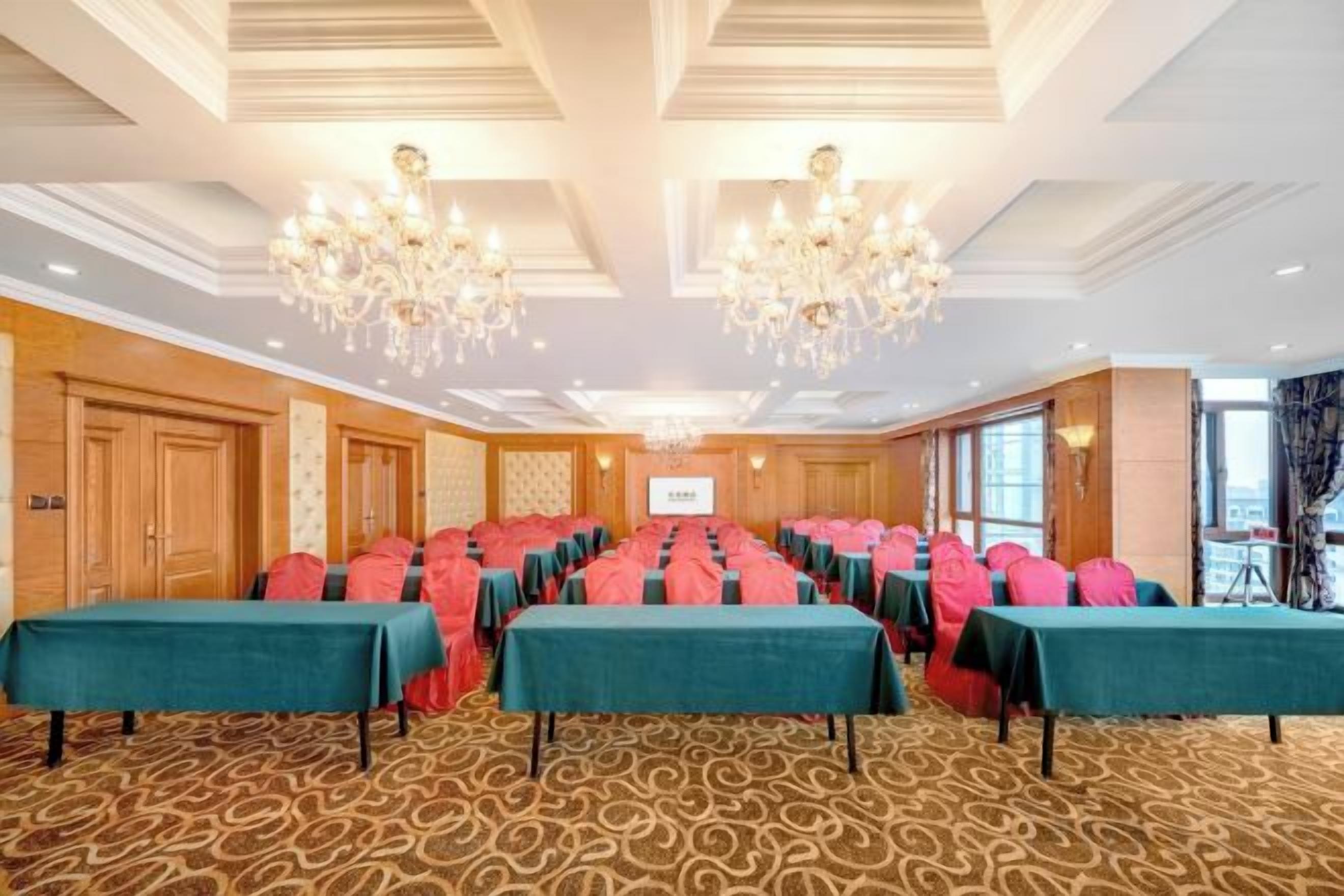A conference room with long tables, chandeliers, and a carpeted floor.