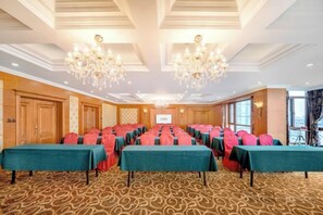 A conference room with long tables, chandeliers, and a carpeted floor. - Donglong Hotel (Harbin)