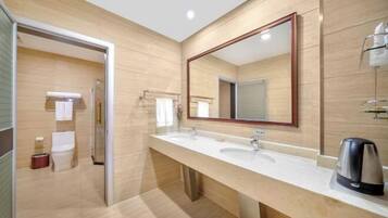 Un baño moderno con un tocador amplio, dos lavamanos, un espejo grande y una cafetera.
