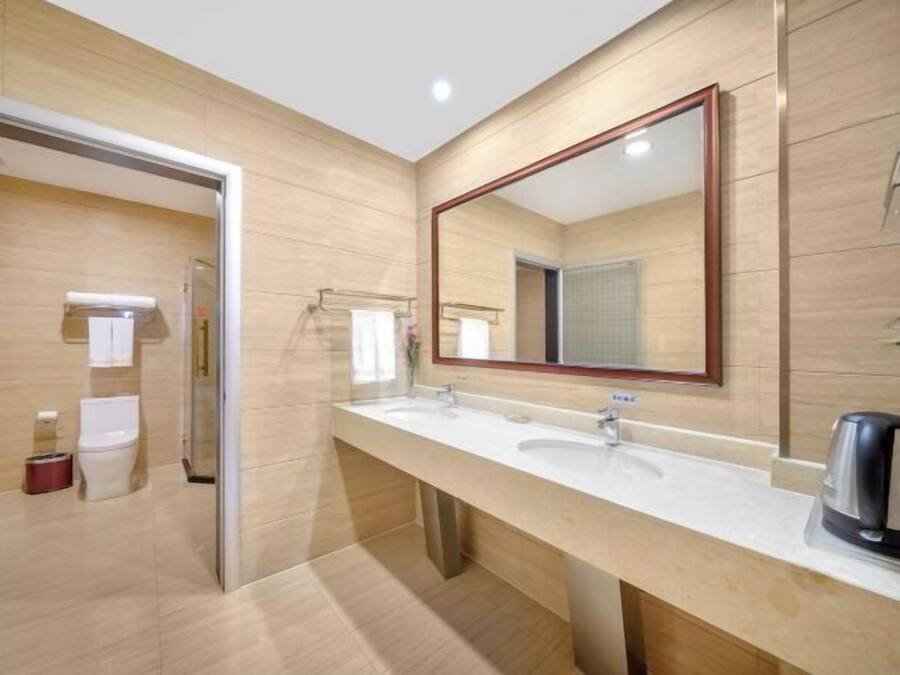 Un baño moderno con un tocador amplio, dos lavamanos, un espejo grande y una cafetera.