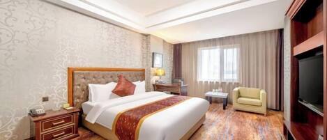 A hotel room with a large bed, a TV, a desk, and a chair.