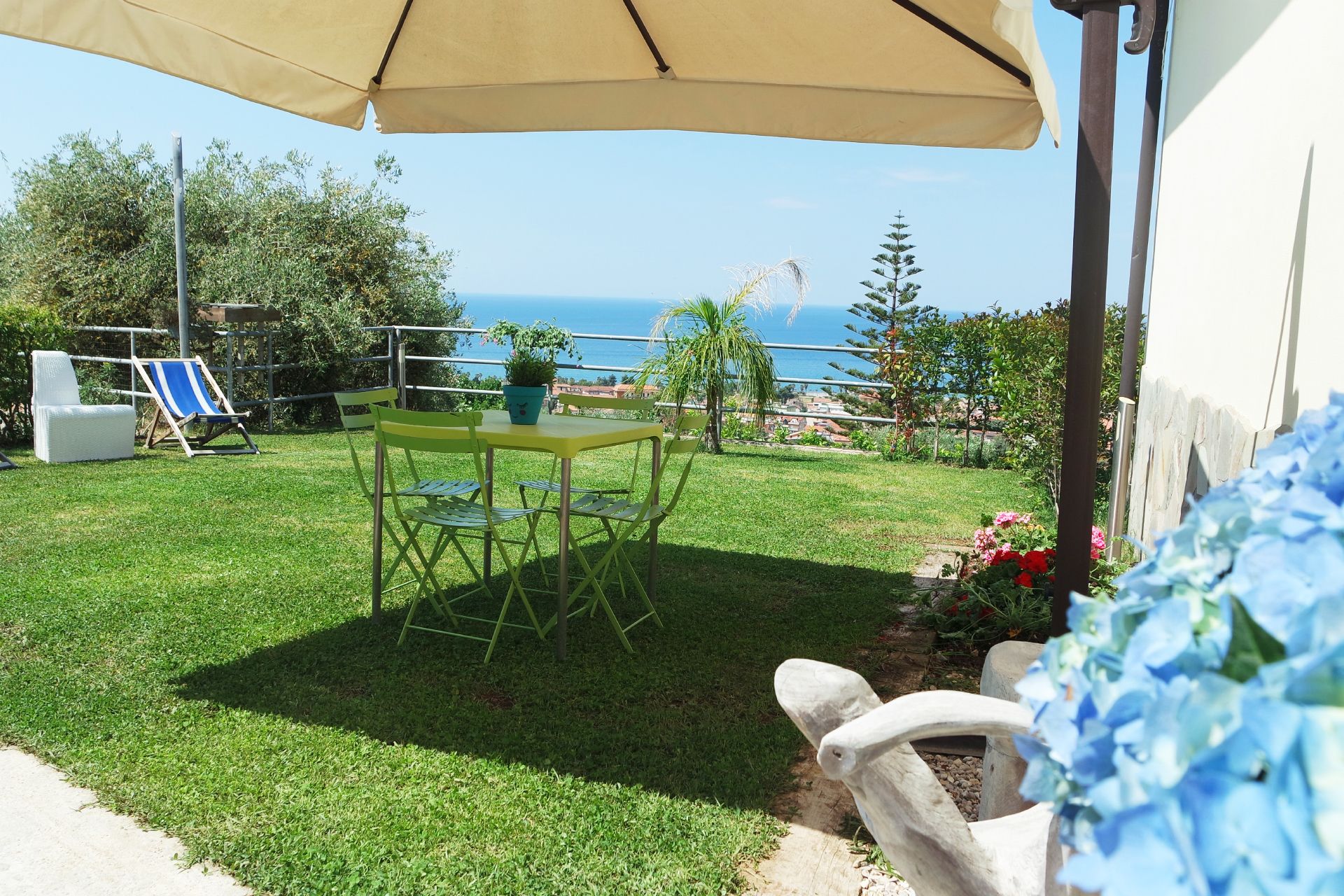Un patio con una mesa y sillas, una planta en maceta y vista al mar.