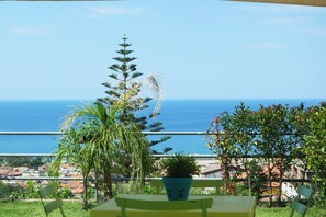 A balcony with a view of the sea, a potted plant, and a table. - Cilento Apartment (Ascea)