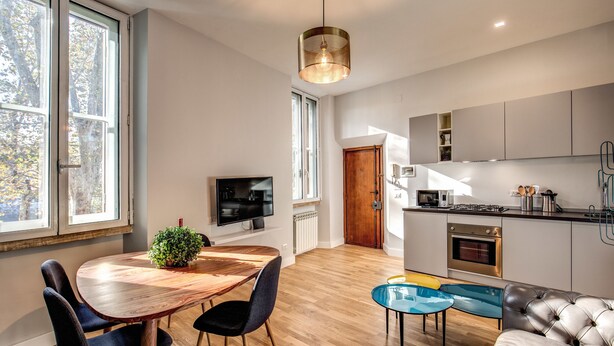 Une cuisine moderne avec une table à manger en bois, des chaises et un téléviseur.