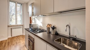 Une cuisine moderne dotée d’une cuisinière intégrée, d’un évier en acier inoxydable et d’une fenêtre avec stores.