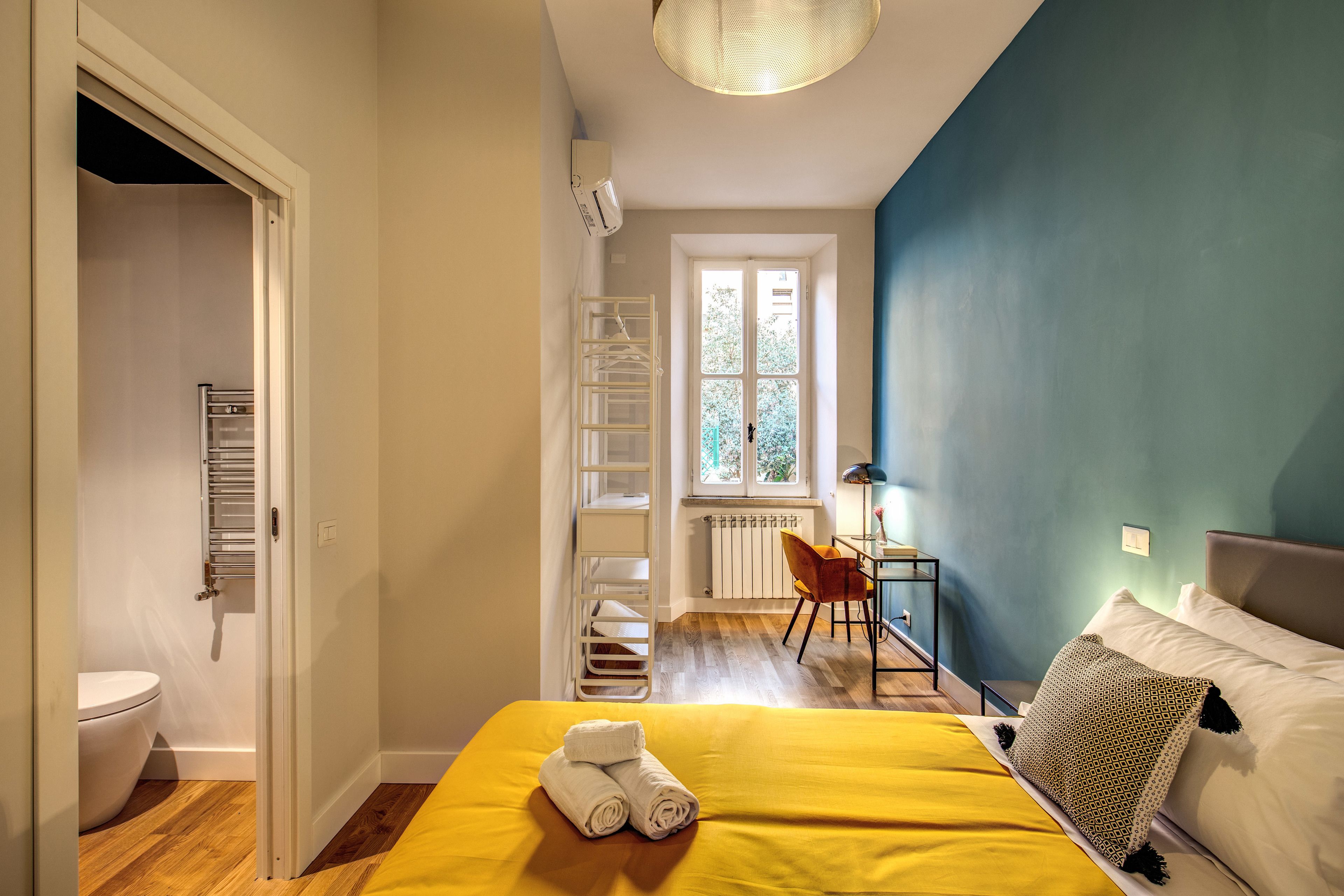 Une chambre à coucher avec un lit, une fenêtre, un radiateur, un bureau et une chaise.