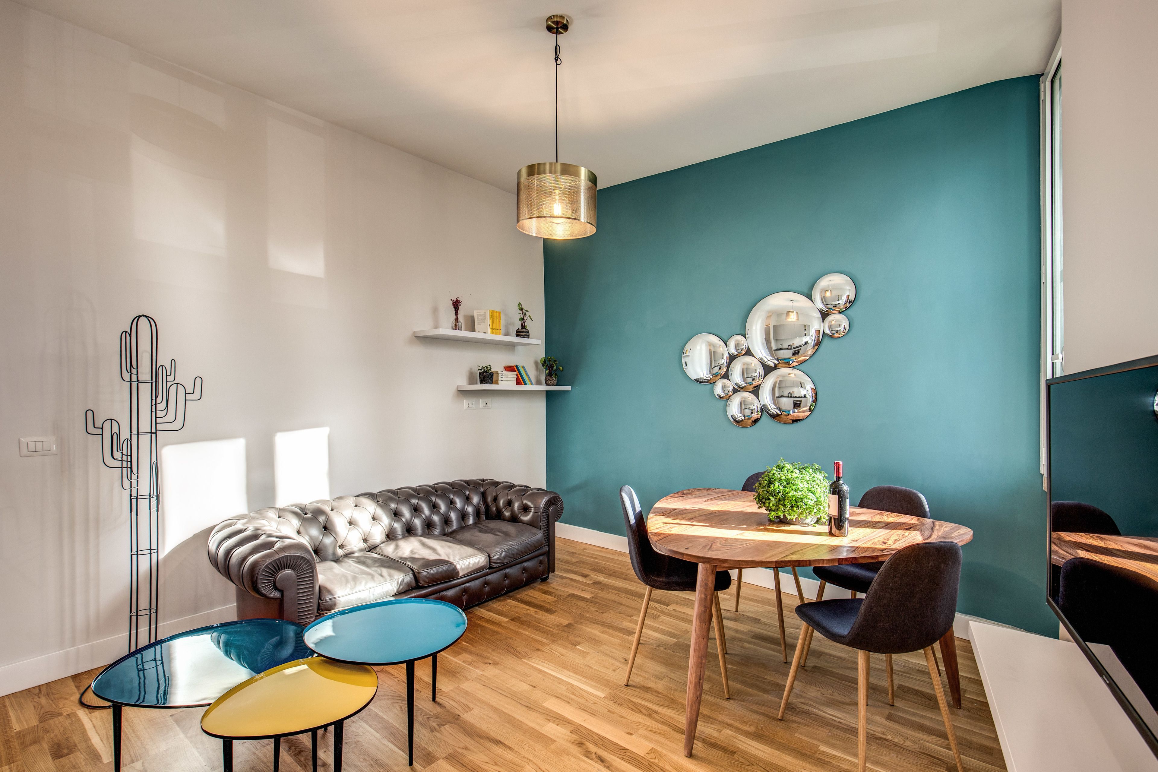 En moderne stue med sofa, spisebord med stole og en pendel.