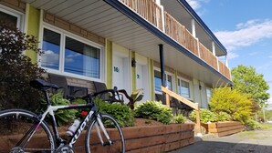 A building with a balcony, wooden steps, and a bicycle parked in front. - Auberge Happy Logis (Lac-Etchemin)