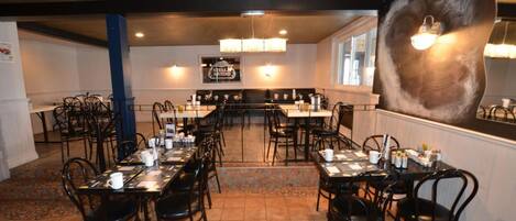 Un restaurante con varias mesas y sillas, un candelabro y un espejo decorativo grande.