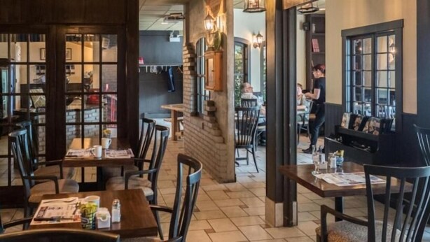 A restaurant with wooden tables and chairs, brick walls, and a cozy atmosphere. - Auberge Happy Logis (Lac-Etchemin)