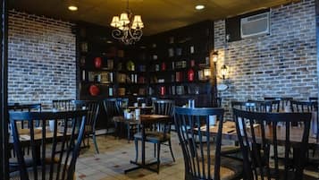 A cozy cafe with brick walls, bookshelves, and wooden tables and chairs.