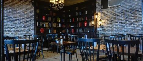 Un café acogedor con paredes de ladrillo, estanterías y mesas y sillas de madera.