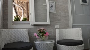 Two wicker chairs with black cushions, a small round table with a flower arrangement, and a framed sign indicating a smoking area. - Ca dei Nobili (Genoa)