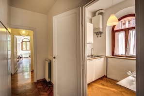 Stylish hallway leads to a kitchen with a sink, window, and pendant light.