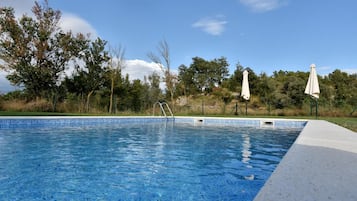 Una piscina al aire libre, sombrillas, sillones reclinables de piscina