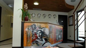 En reception med et muralmaleri, et ur og en potteplante.