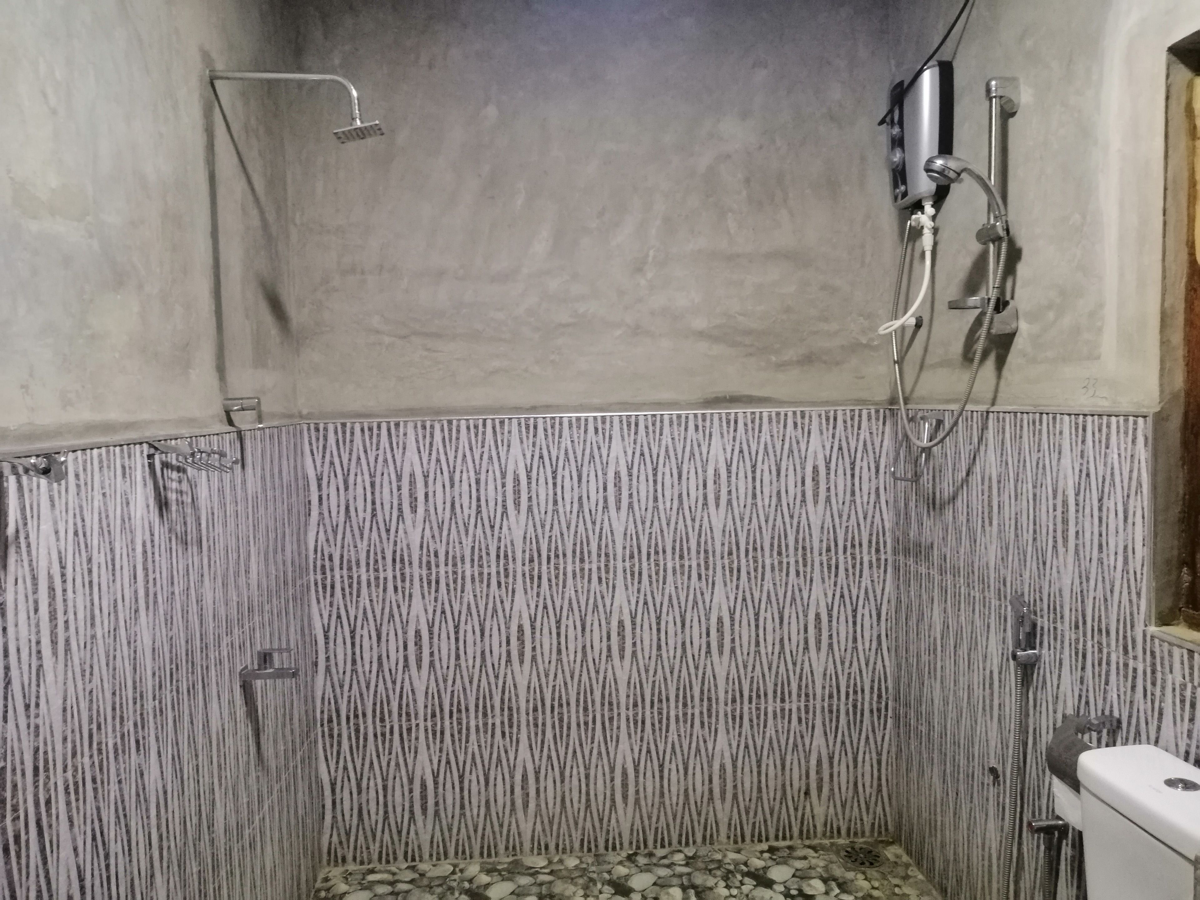 A small, enclosed shower area with a tiled floor and a showerhead mounted on the wall.