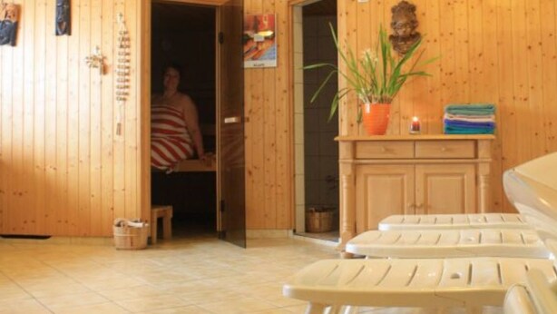 Een houten interieur met een sauna, inclusief banken en een deur.