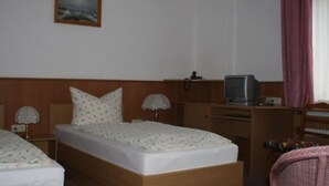 Een hotelkamer met twee bedden, een televisie en een bureau.