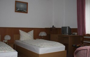 Een hotelkamer met twee bedden, een televisie en een bureau.