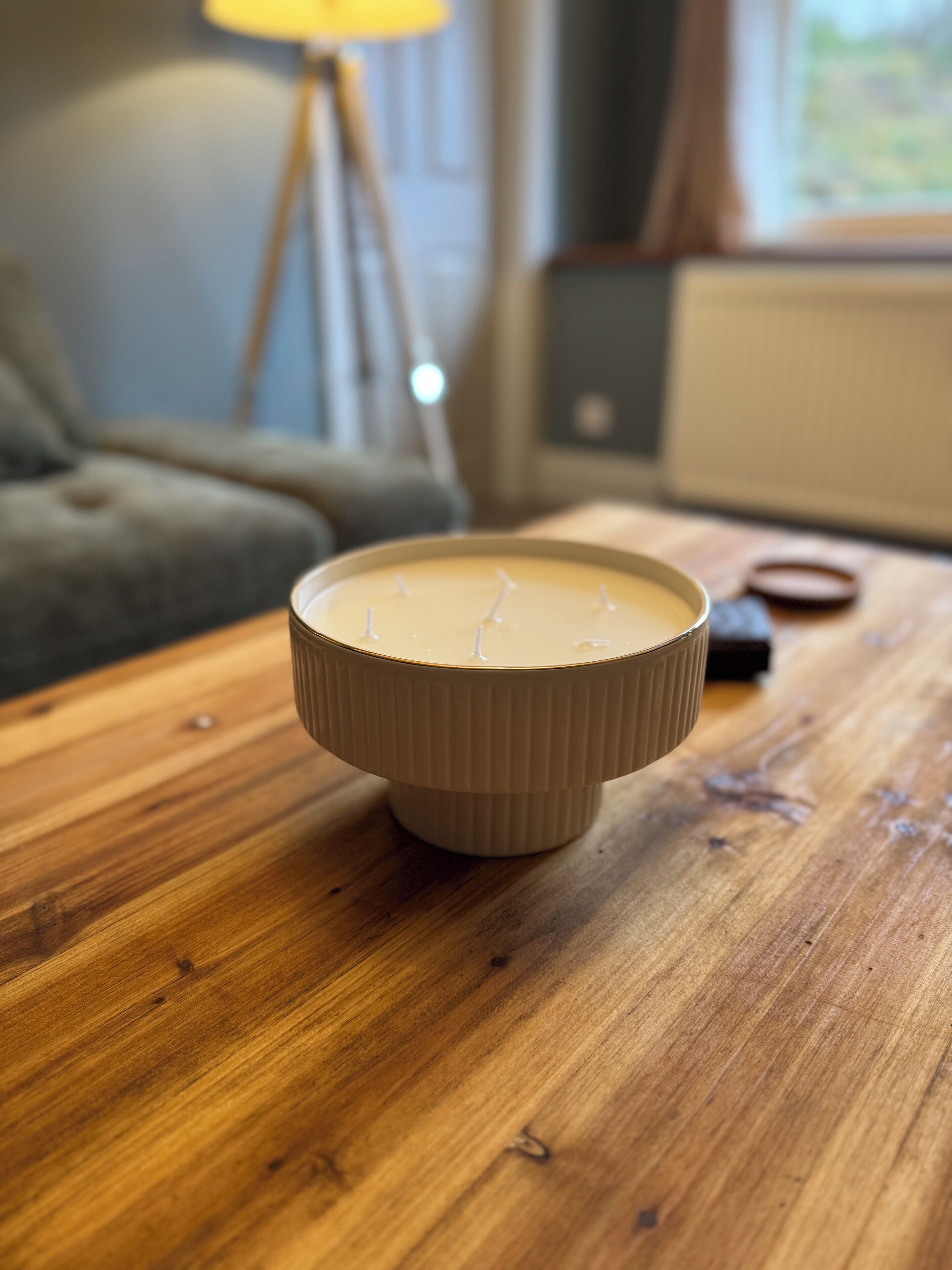A candle in a ribbed holder on a wooden table.