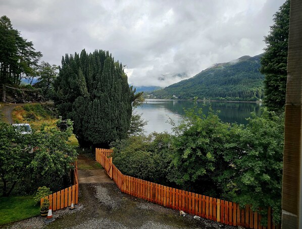 A view of a river with a wooden fence and trees.