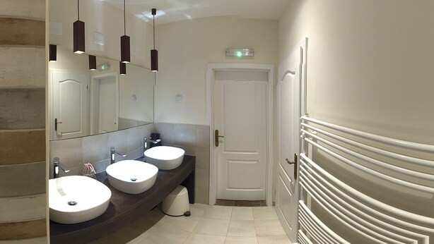 A modern bathroom with two sinks, a large mirror, and a door. - Zagreb Speeka Hostel (Zagreb)