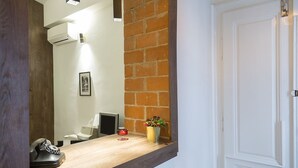 Un área de recepción con un mostrador de madera, un teléfono, una vela roja y un jarrón con flores.