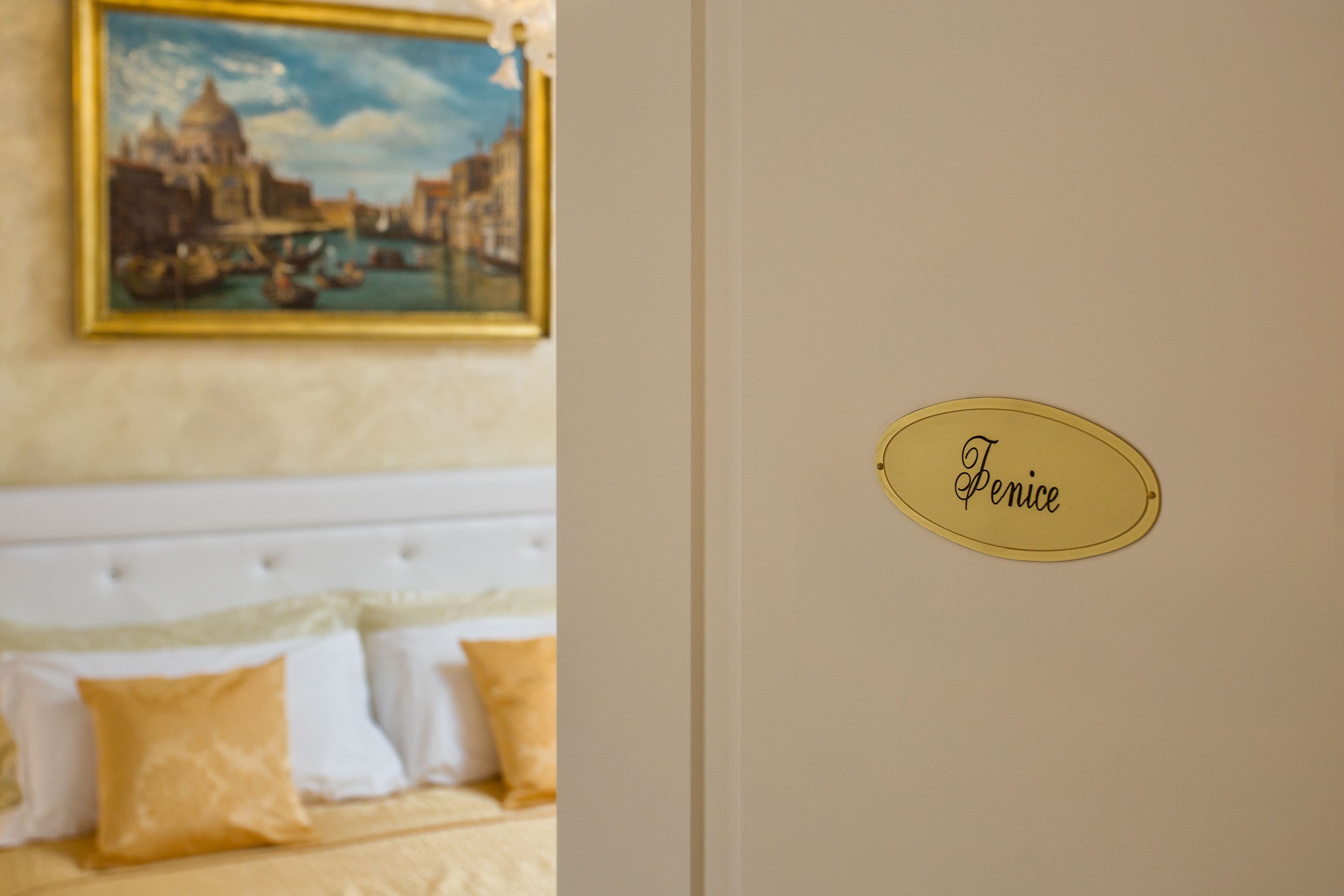 A room with a bed, a painting of Venice, and a sign that says "Penice".