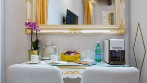 A hotel room with a white leather sofa, a coffee table with a white cup, a yellow basket, a green bottle, and a coffee machine labeled "MOKADOR". - Cà Patron (Venice)
