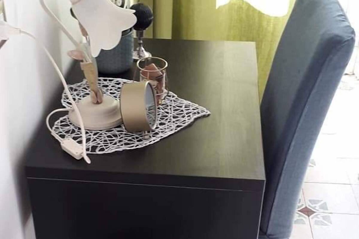Un petit coin repas avec une table et une chaise, une lampe, ainsi qu’un plateau contenant des verres et un bol.