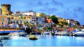 A coastal town with historic buildings, a castle, and a marina with boats. - Domus Linda B&B (Forio)